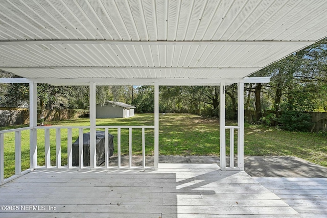 deck with a fenced backyard, a yard, an outdoor structure, and a storage unit