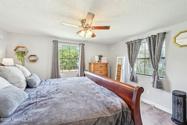 bedroom featuring ceiling fan, a textured ceiling, wood finished floors, and baseboards