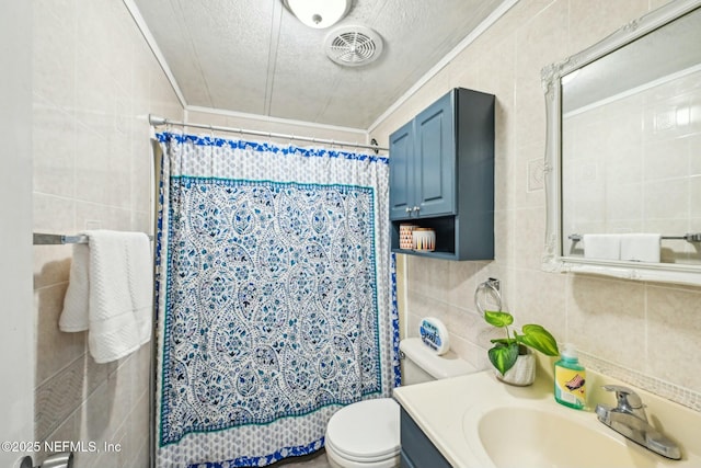 full bath with visible vents, toilet, a textured ceiling, vanity, and tile walls