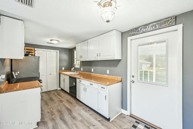 kitchen featuring light wood-style floors, visible vents, white cabinets, and dishwasher