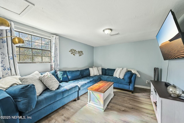 living room featuring baseboards, attic access, visible vents, and wood finished floors