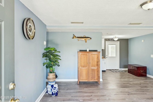 interior space with visible vents, baseboards, and wood finished floors