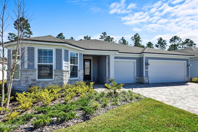 view of front of property featuring a garage, stone siding, and decorative driveway