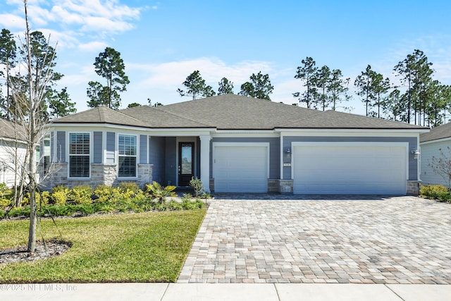 view of front of house featuring a garage, a front yard, stone siding, and decorative driveway