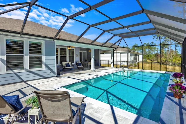 view of swimming pool with glass enclosure, a fenced in pool, a ceiling fan, and a patio