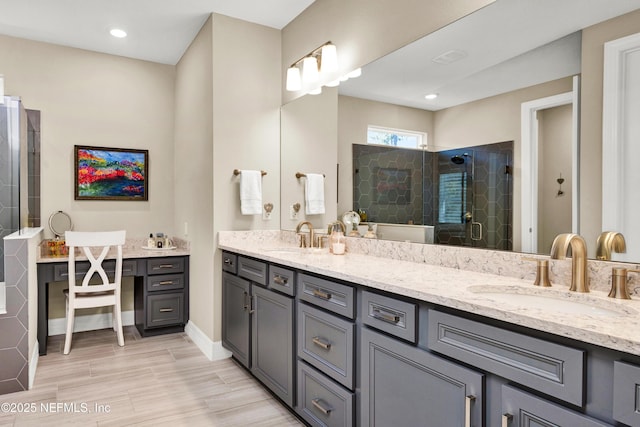 full bathroom with double vanity, a stall shower, baseboards, and a sink