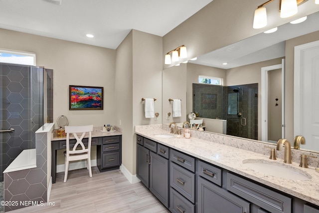 bathroom featuring double vanity, tiled shower, a sink, and baseboards