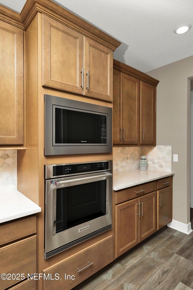 kitchen with wood finished floors, stainless steel appliances, decorative backsplash, and light countertops