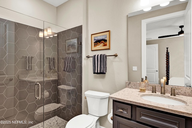 bathroom with a stall shower, vanity, toilet, and a ceiling fan