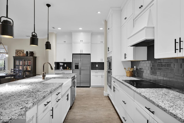 kitchen with crown molding, white cabinets, premium range hood, and stainless steel appliances