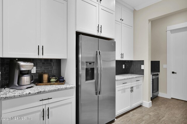 kitchen with light wood-style flooring, stainless steel refrigerator with ice dispenser, light stone counters, backsplash, and white cabinets