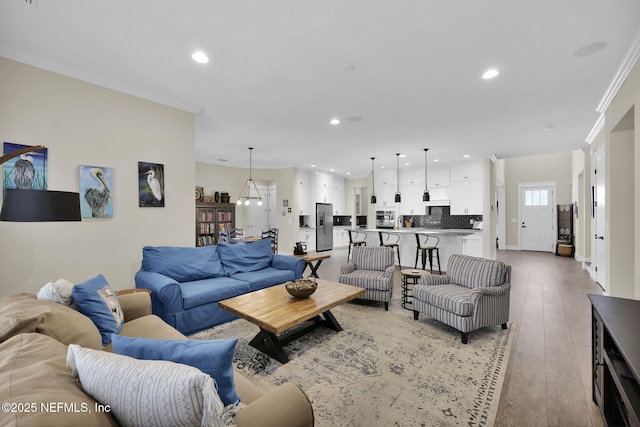 living area featuring recessed lighting, light wood-style flooring, and crown molding