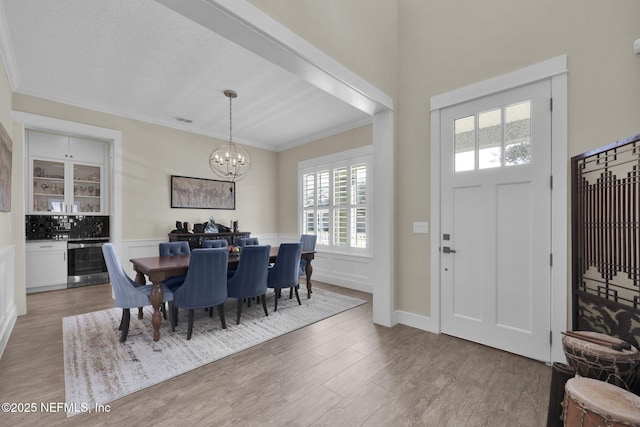 entryway with wine cooler, an inviting chandelier, wood finished floors, and crown molding