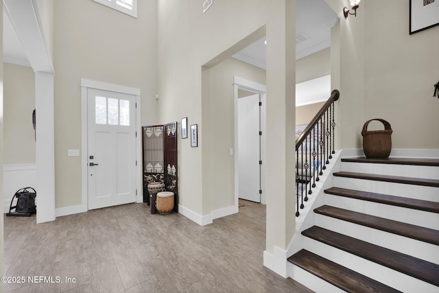 entryway featuring stairway, baseboards, a towering ceiling, and ornamental molding