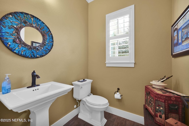 bathroom with a sink, toilet, baseboards, and wood finished floors