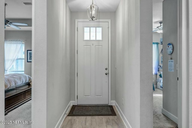 entryway featuring ceiling fan, wood finished floors, visible vents, and baseboards