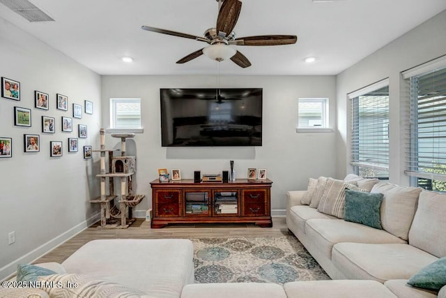 living area featuring a ceiling fan, baseboards, visible vents, and wood finished floors