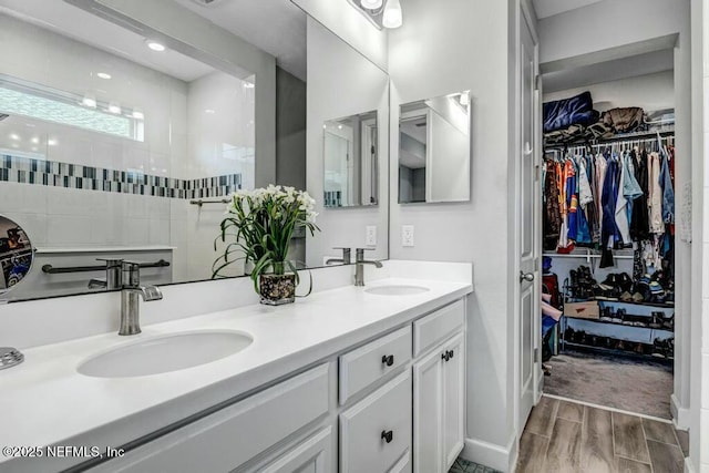 full bathroom featuring a walk in shower, a sink, a spacious closet, and double vanity