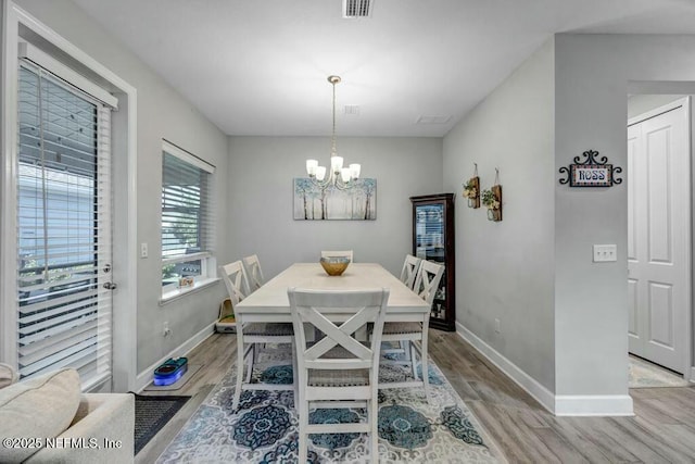 dining area with baseboards, visible vents, an inviting chandelier, and wood finished floors