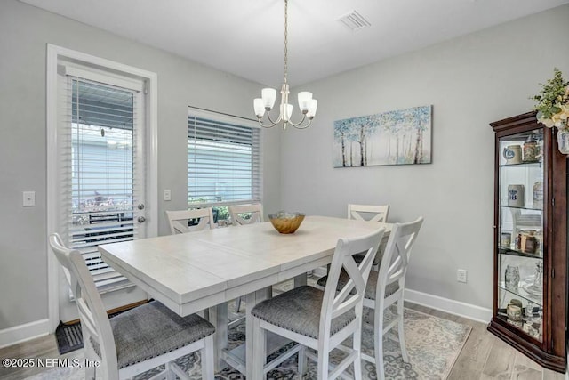 dining room featuring light wood-style flooring, visible vents, a chandelier, and baseboards