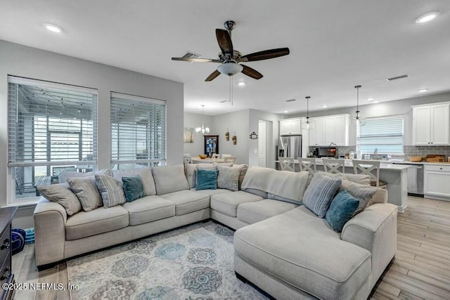 living area featuring ceiling fan with notable chandelier, visible vents, light wood-style flooring, and recessed lighting