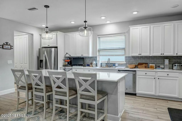 kitchen featuring stainless steel appliances, light wood-type flooring, backsplash, and a kitchen breakfast bar