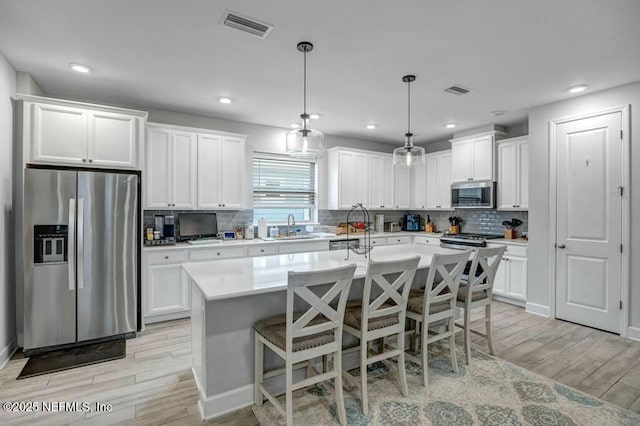 kitchen featuring appliances with stainless steel finishes, wood tiled floor, visible vents, and a sink