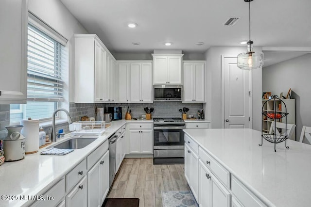 kitchen featuring stainless steel appliances, a sink, light countertops, and white cabinets