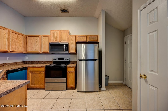 kitchen featuring light tile patterned floors, a textured ceiling, lofted ceiling, visible vents, and appliances with stainless steel finishes