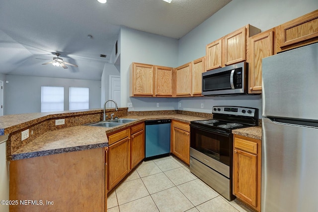 kitchen featuring light tile patterned floors, a ceiling fan, appliances with stainless steel finishes, a peninsula, and a sink