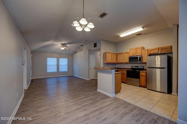 kitchen with visible vents, light wood-style floors, open floor plan, vaulted ceiling, and appliances with stainless steel finishes