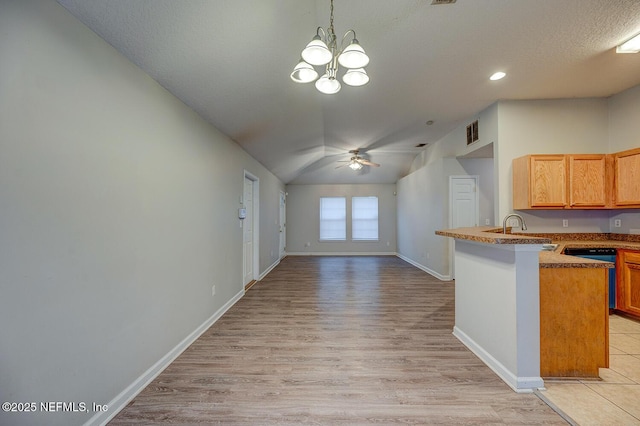 kitchen featuring ceiling fan with notable chandelier, a peninsula, a sink, baseboards, and open floor plan