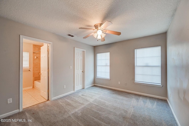 unfurnished bedroom featuring carpet, a textured ceiling, visible vents, and baseboards