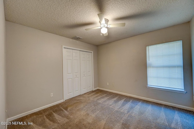 unfurnished bedroom featuring carpet floors, a closet, visible vents, a ceiling fan, and baseboards