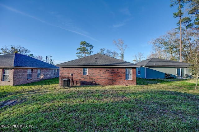 back of house featuring brick siding, a yard, and central AC unit