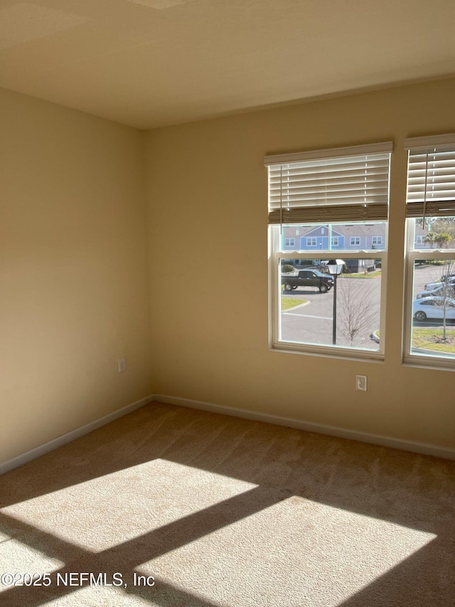 empty room featuring carpet and baseboards