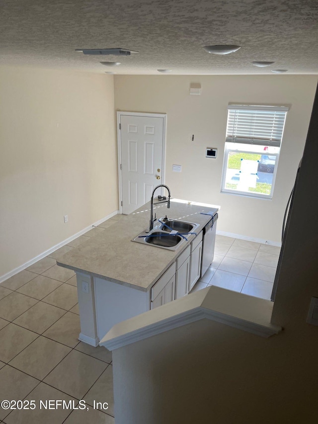 kitchen featuring light tile patterned flooring, a sink, a textured ceiling, and white cabinetry