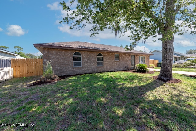 rear view of house with brick siding, fence, and a lawn