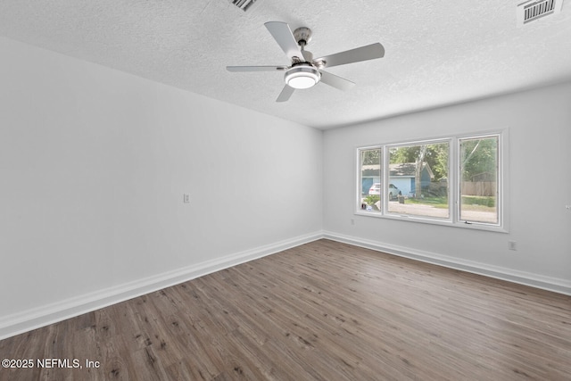 spare room with visible vents, a textured ceiling, baseboards, and wood finished floors