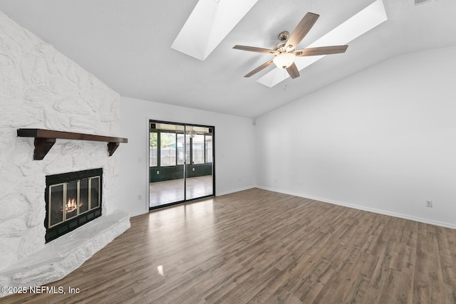 unfurnished living room featuring vaulted ceiling with skylight, baseboards, ceiling fan, wood finished floors, and a fireplace