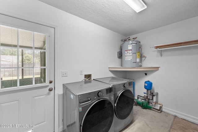 washroom with a textured ceiling, washing machine and dryer, electric water heater, laundry area, and baseboards