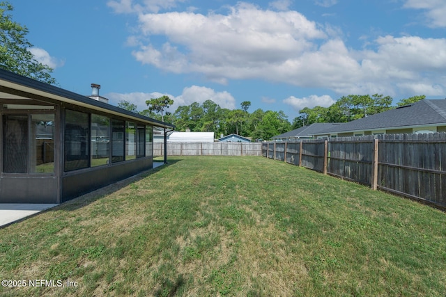 view of yard featuring a sunroom and a fenced backyard