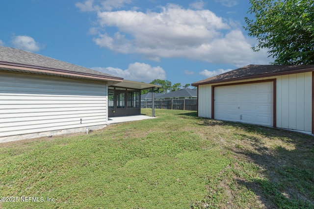 view of yard featuring an outdoor structure, fence, and a sunroom