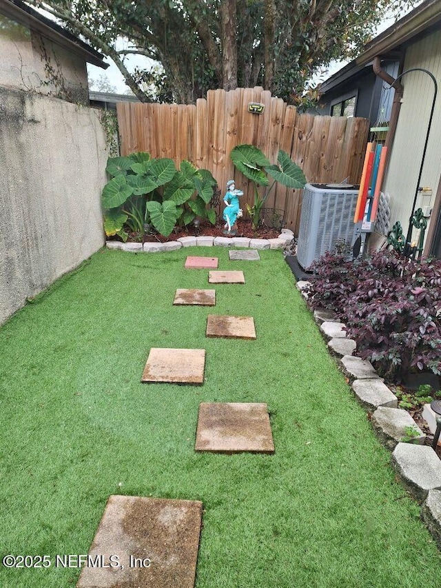 view of yard with central AC and fence