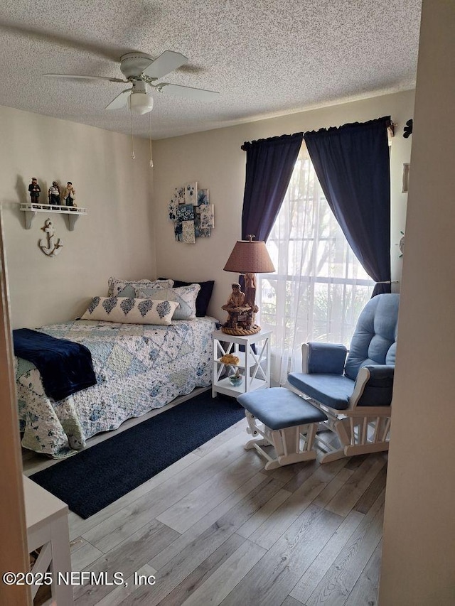 bedroom featuring a ceiling fan, a textured ceiling, and wood finished floors