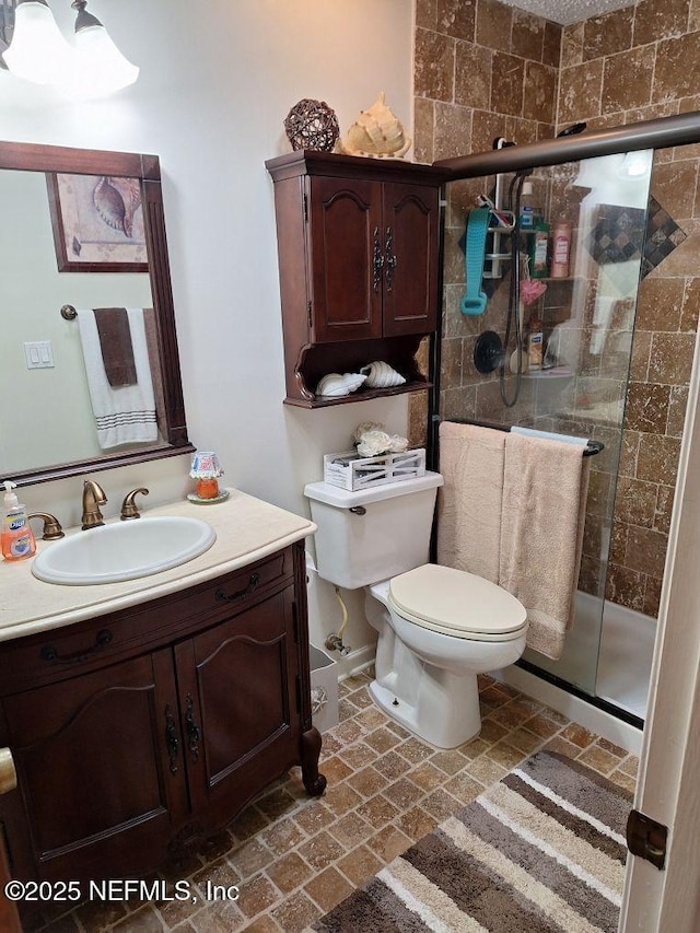 full bathroom featuring a shower stall, toilet, and vanity