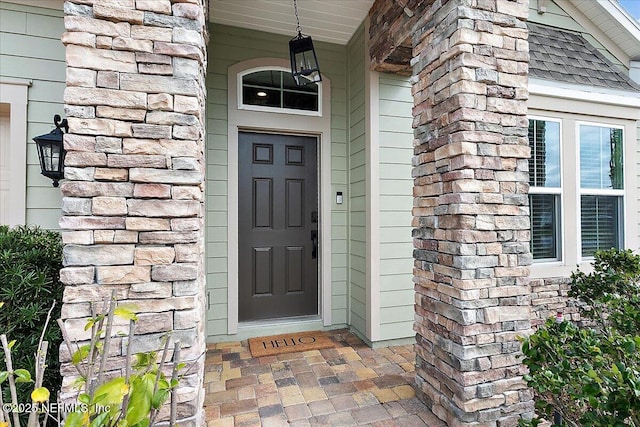 property entrance featuring stone siding and roof with shingles