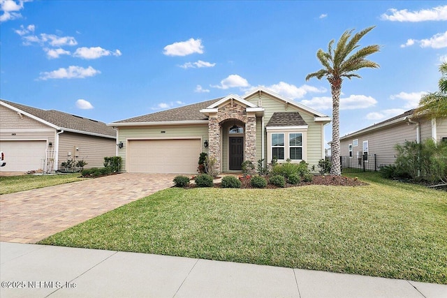 view of front of home featuring stone siding, an attached garage, fence, decorative driveway, and a front lawn