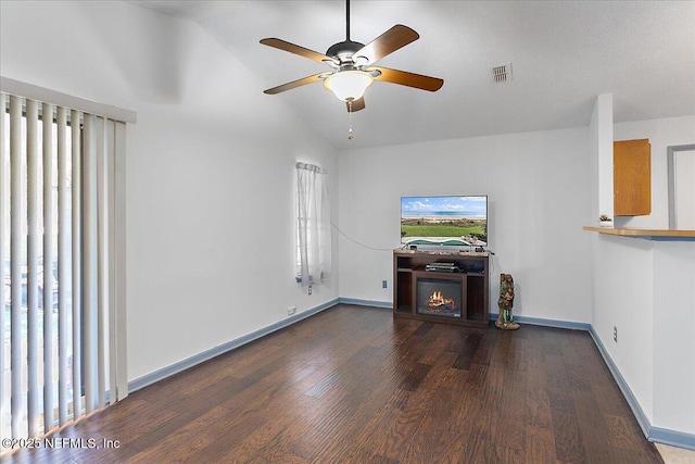 unfurnished living room with a wealth of natural light, visible vents, a lit fireplace, and wood finished floors