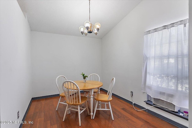 dining space with vaulted ceiling, baseboards, an inviting chandelier, and wood finished floors